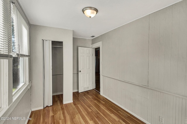 unfurnished bedroom featuring hardwood / wood-style floors and wood walls