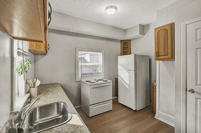 kitchen with a textured ceiling, white appliances, dark hardwood / wood-style floors, and sink