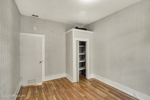 unfurnished bedroom featuring light hardwood / wood-style floors, a textured ceiling, and a closet