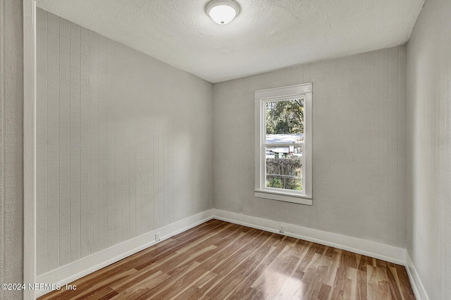 unfurnished room with hardwood / wood-style floors and a textured ceiling