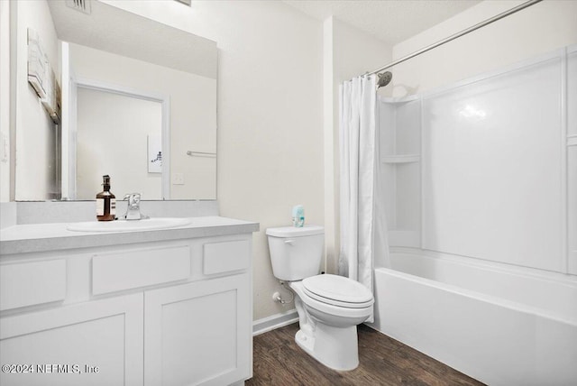 full bathroom with vanity, a textured ceiling, shower / bath combo with shower curtain, hardwood / wood-style floors, and toilet