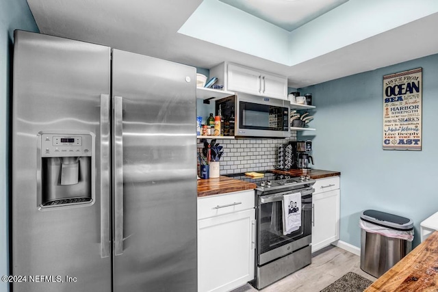 kitchen with white cabinetry, light hardwood / wood-style flooring, wooden counters, decorative backsplash, and appliances with stainless steel finishes