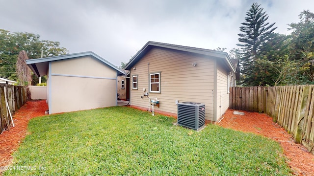 rear view of property featuring central AC unit and a lawn