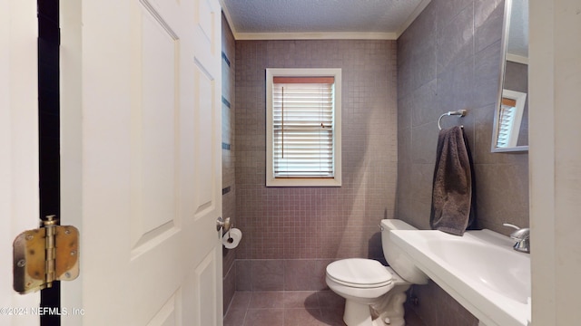 bathroom featuring tile patterned floors, a textured ceiling, sink, tile walls, and toilet