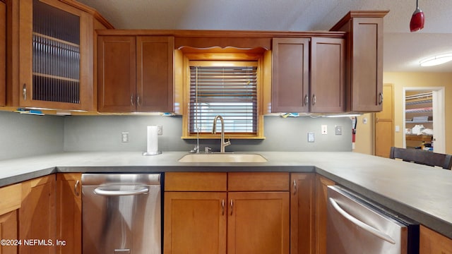 kitchen with a textured ceiling, dishwasher, sink, and decorative light fixtures