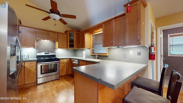 kitchen featuring kitchen peninsula, appliances with stainless steel finishes, light wood-type flooring, sink, and a breakfast bar area