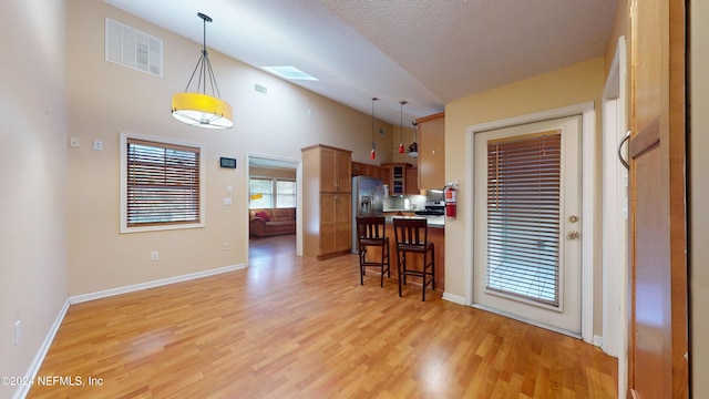 kitchen with a skylight, pendant lighting, a textured ceiling, a kitchen bar, and light wood-type flooring