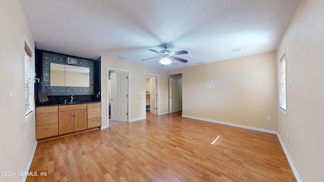 unfurnished bedroom featuring a textured ceiling, ceiling fan, light hardwood / wood-style floors, and sink