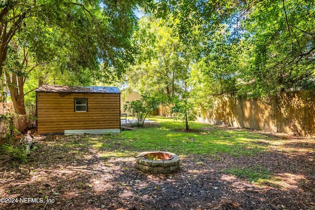 view of yard with a shed and an outdoor fire pit