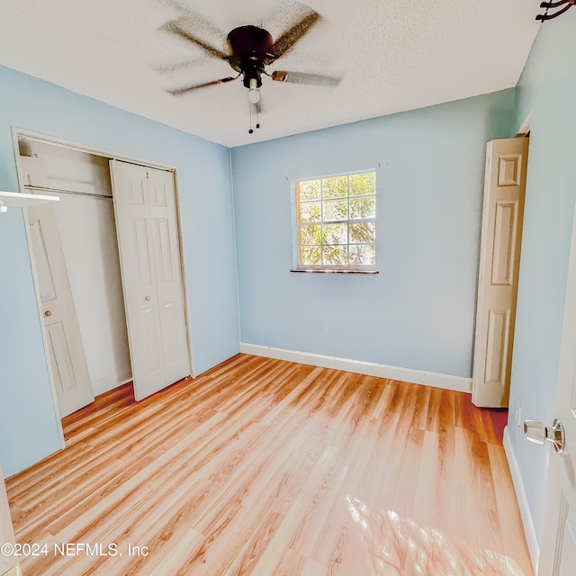 unfurnished bedroom with ceiling fan, a closet, a textured ceiling, and light hardwood / wood-style flooring