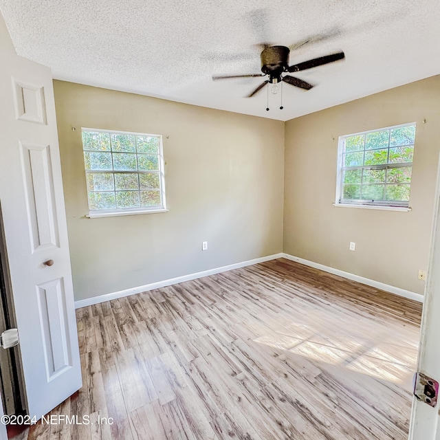 unfurnished room featuring ceiling fan, a healthy amount of sunlight, a textured ceiling, and light hardwood / wood-style floors