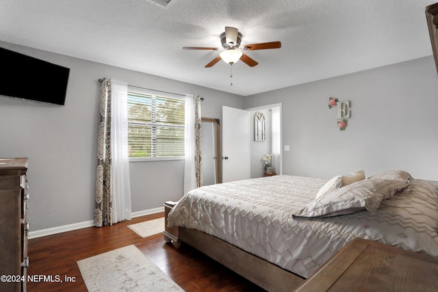 bedroom with ceiling fan, dark wood-type flooring, and a textured ceiling