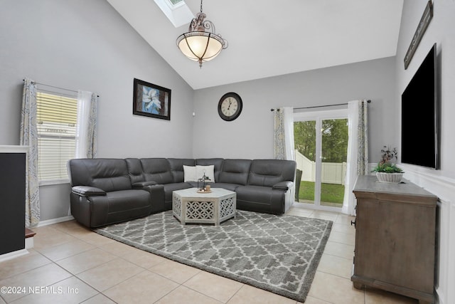 tiled living room featuring high vaulted ceiling and a skylight