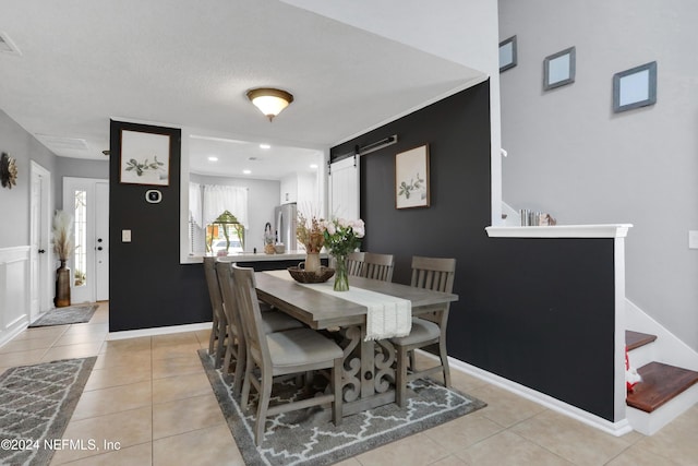 tiled dining area with a textured ceiling and a barn door