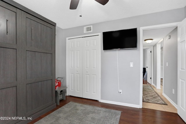 bedroom featuring ceiling fan, dark hardwood / wood-style flooring, and a textured ceiling