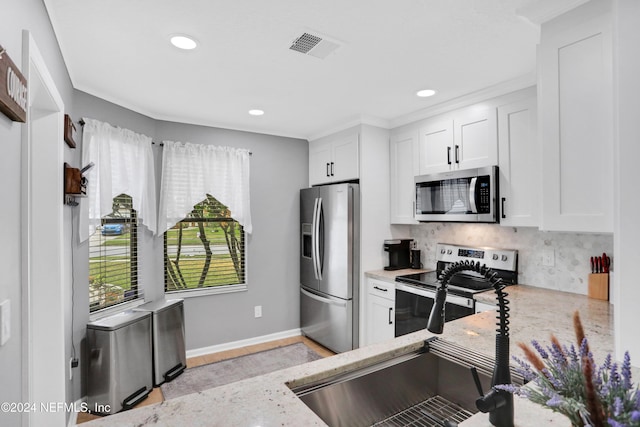 kitchen featuring decorative backsplash, white cabinetry, light stone countertops, and appliances with stainless steel finishes