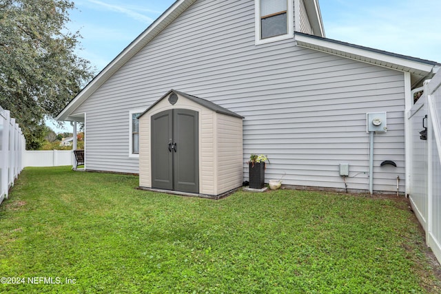 rear view of house featuring a storage unit and a yard