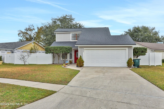 view of property featuring a garage and a front lawn