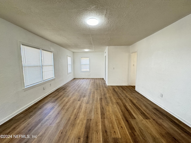 spare room featuring dark hardwood / wood-style floors and a textured ceiling