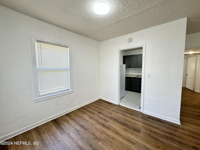 unfurnished room with a textured ceiling and hardwood / wood-style flooring