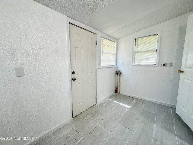 interior space with lofted ceiling, light hardwood / wood-style floors, and a textured ceiling