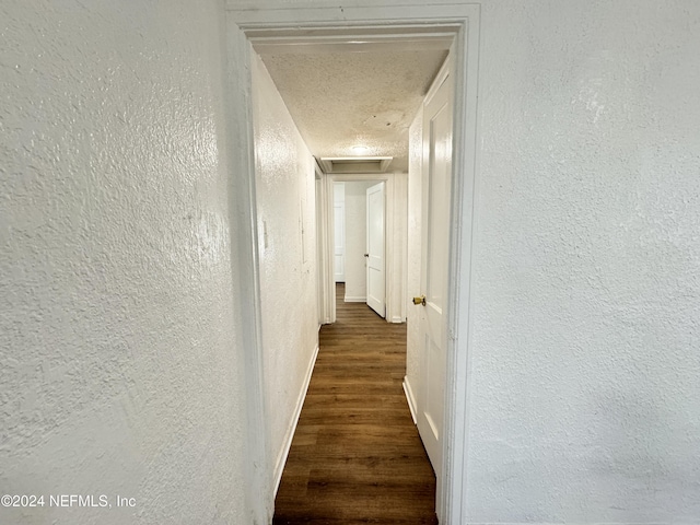 hall featuring a textured ceiling and dark hardwood / wood-style floors