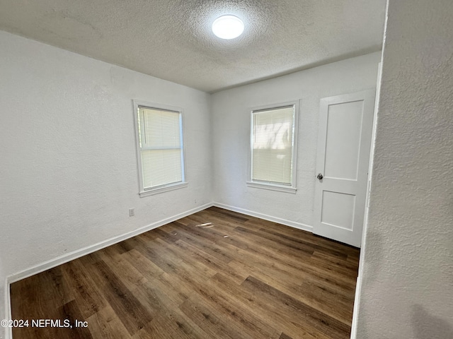 empty room featuring dark wood-type flooring and a textured ceiling