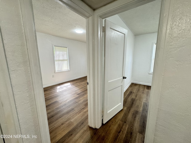 hallway with a textured ceiling and dark wood-type flooring