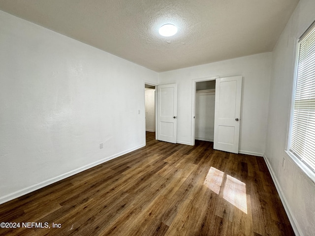 unfurnished bedroom featuring a textured ceiling and dark hardwood / wood-style floors