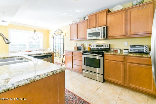 kitchen with appliances with stainless steel finishes, ornamental molding, sink, pendant lighting, and light tile patterned flooring