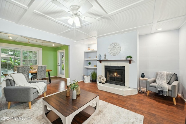 living room featuring a tile fireplace, wood-type flooring, ceiling fan, and beamed ceiling