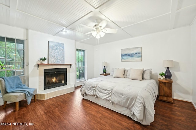 bedroom with a tile fireplace, dark hardwood / wood-style floors, and ceiling fan