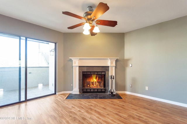 unfurnished living room featuring hardwood / wood-style floors, ceiling fan, and a tiled fireplace