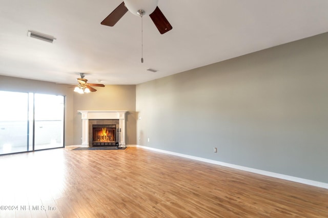 unfurnished living room featuring ceiling fan, wood-type flooring, and a fireplace