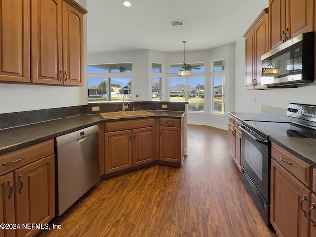 kitchen with hanging light fixtures, sink, dark wood-type flooring, and appliances with stainless steel finishes