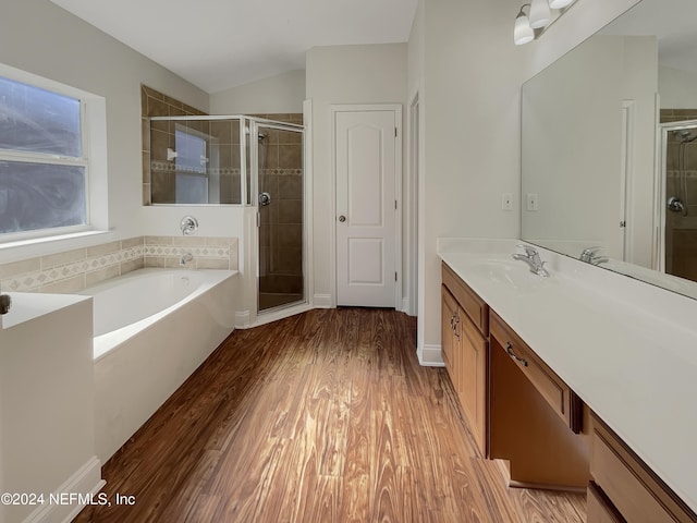 bathroom featuring vanity, wood-type flooring, shower with separate bathtub, and vaulted ceiling