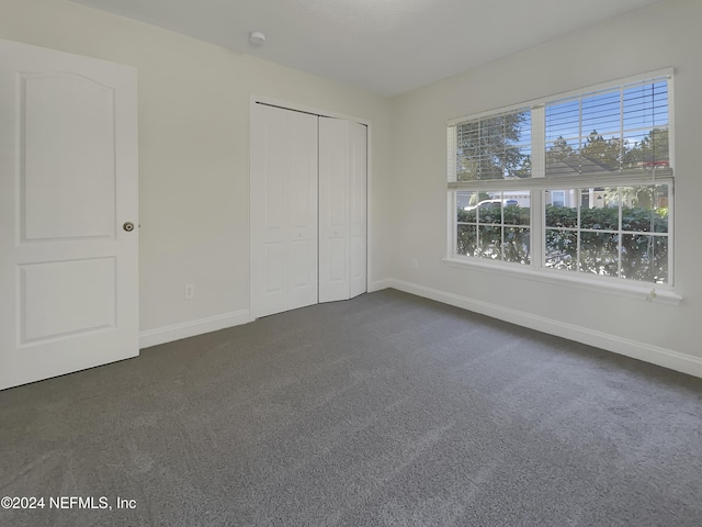 unfurnished bedroom featuring a closet, a water view, and dark carpet