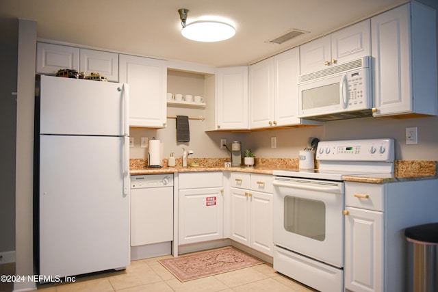 kitchen with light stone countertops, light tile patterned floors, white cabinets, and white appliances