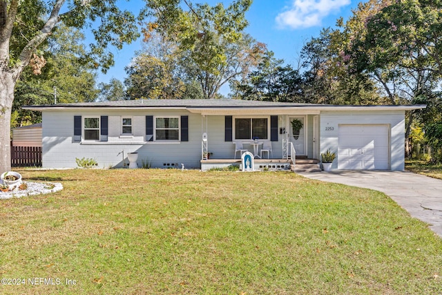 single story home featuring covered porch, a garage, and a front yard