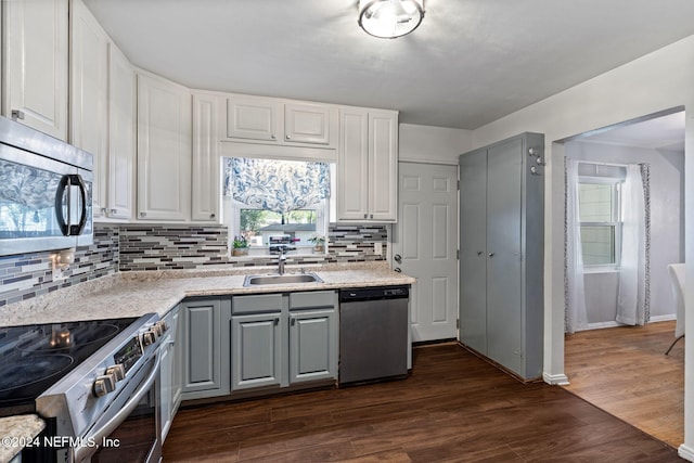 kitchen with appliances with stainless steel finishes, tasteful backsplash, dark wood-type flooring, sink, and white cabinetry