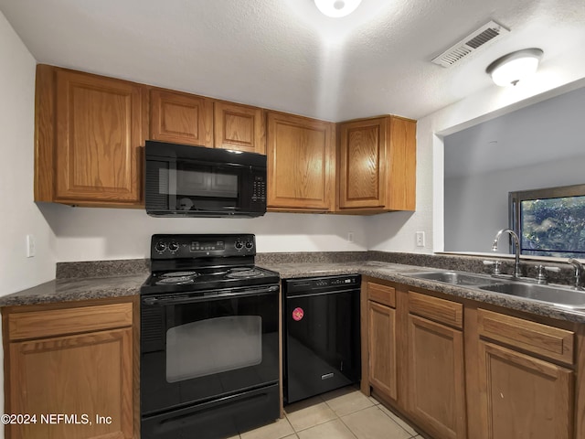 kitchen with sink, light tile patterned floors, black appliances, and a textured ceiling