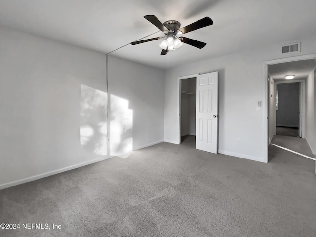 unfurnished bedroom featuring dark colored carpet, ceiling fan, and a closet