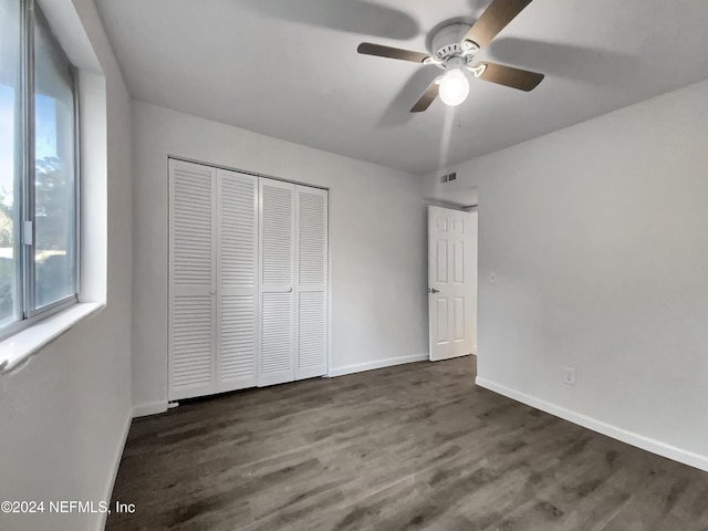 unfurnished bedroom with a closet, ceiling fan, and dark hardwood / wood-style flooring