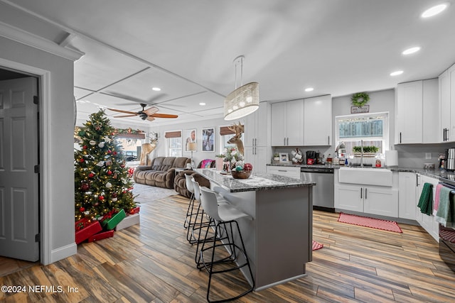 kitchen with white cabinets, dishwasher, a center island, and hardwood / wood-style floors