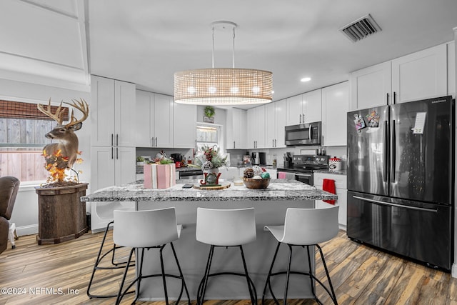 kitchen with white cabinets, a healthy amount of sunlight, light hardwood / wood-style floors, and stainless steel appliances