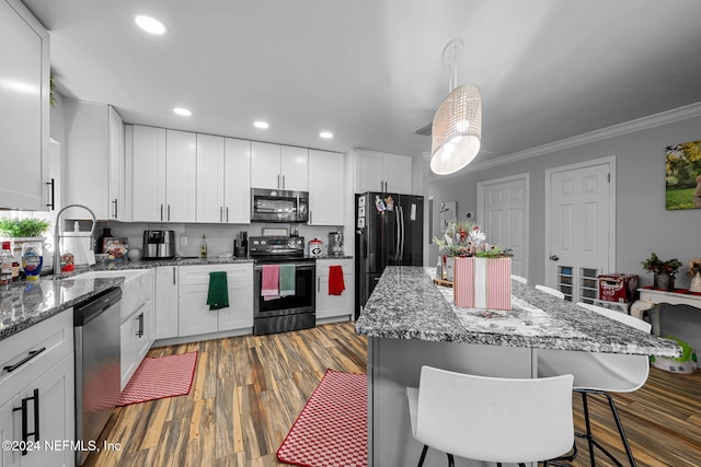 kitchen with dark hardwood / wood-style flooring, ornamental molding, a kitchen island, black appliances, and white cabinetry