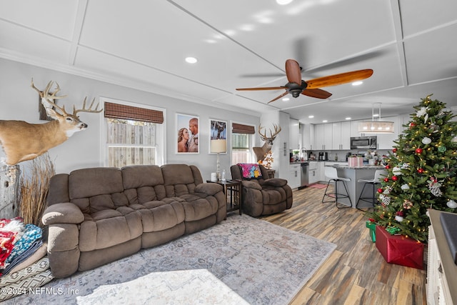 living room with ceiling fan, a healthy amount of sunlight, ornamental molding, and dark wood-type flooring