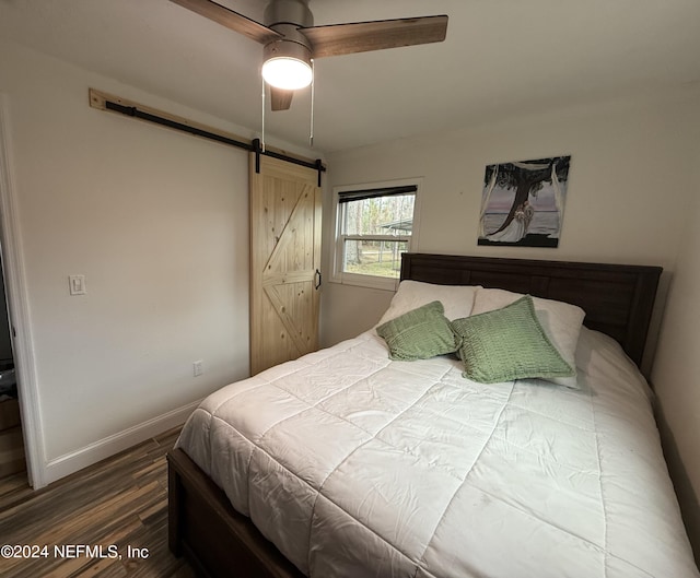 bedroom with hardwood / wood-style flooring, ceiling fan, and a barn door