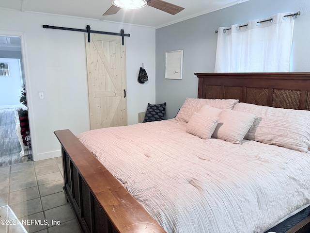 tiled bedroom with ceiling fan, a barn door, and ornamental molding