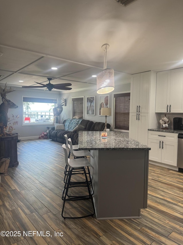 130 Cedar Creek Rd, Palatka, FL 32177 - kitchen with a kitchen island, open floor plan, dark stone countertops, a breakfast bar, and white cabinetry